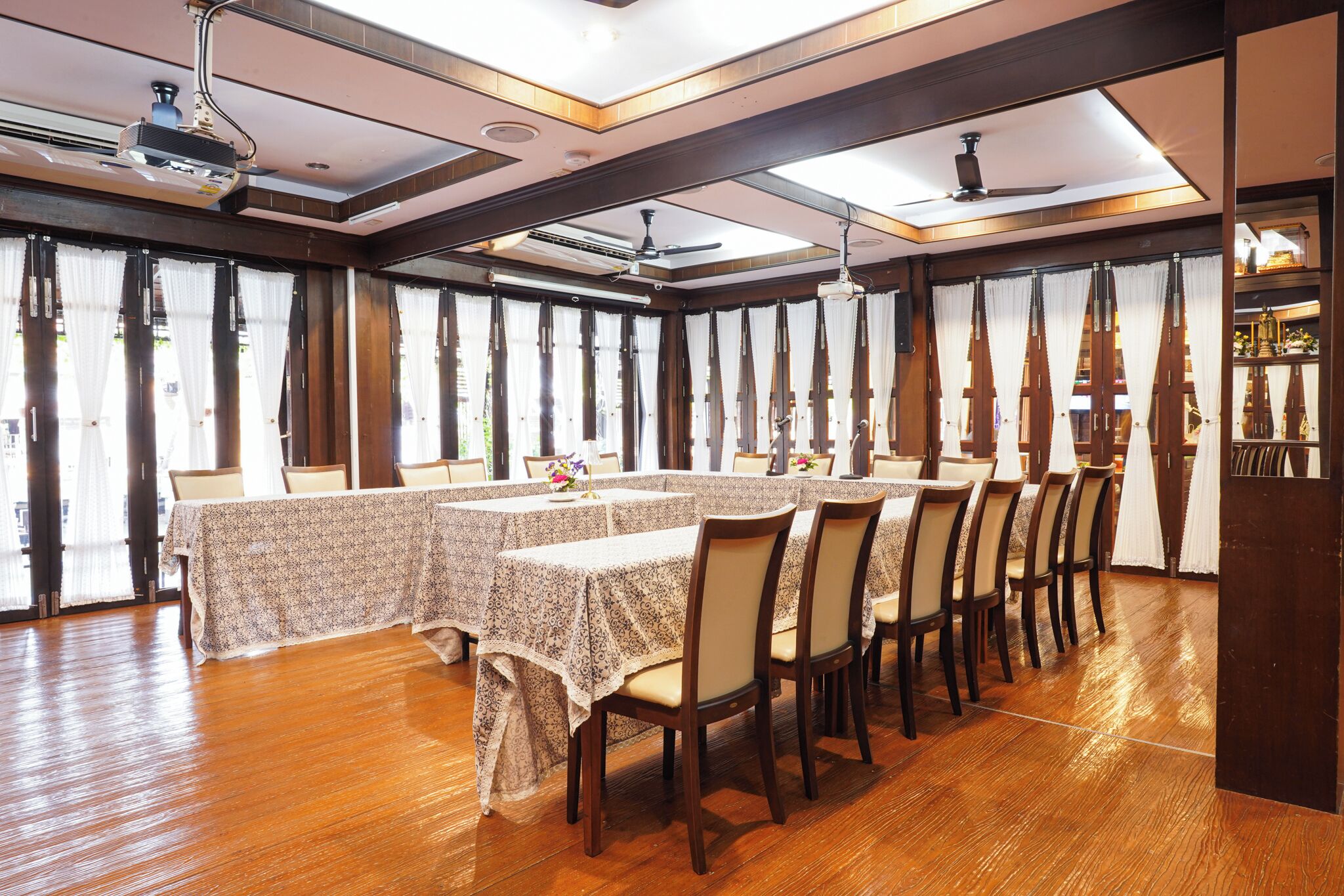 A dining area with long tables, chairs, and a ceiling fan.