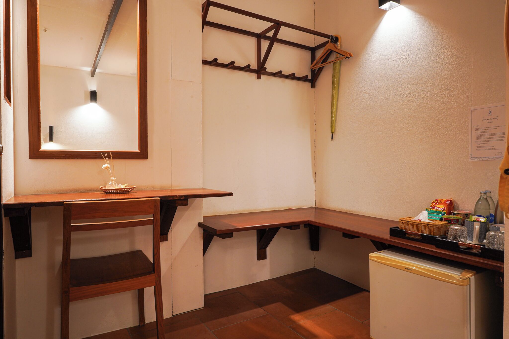 Une cuisine compacte avec un comptoir en bois, un petit réfrigérateur et un étendoir suspendu.