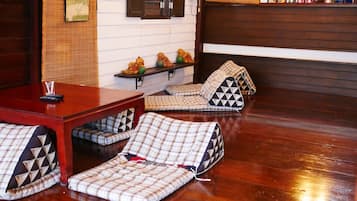 Ein gemütliches Zimmer mit Holzboden, einem roten Tisch und einer Bank mit karierten Kissen.