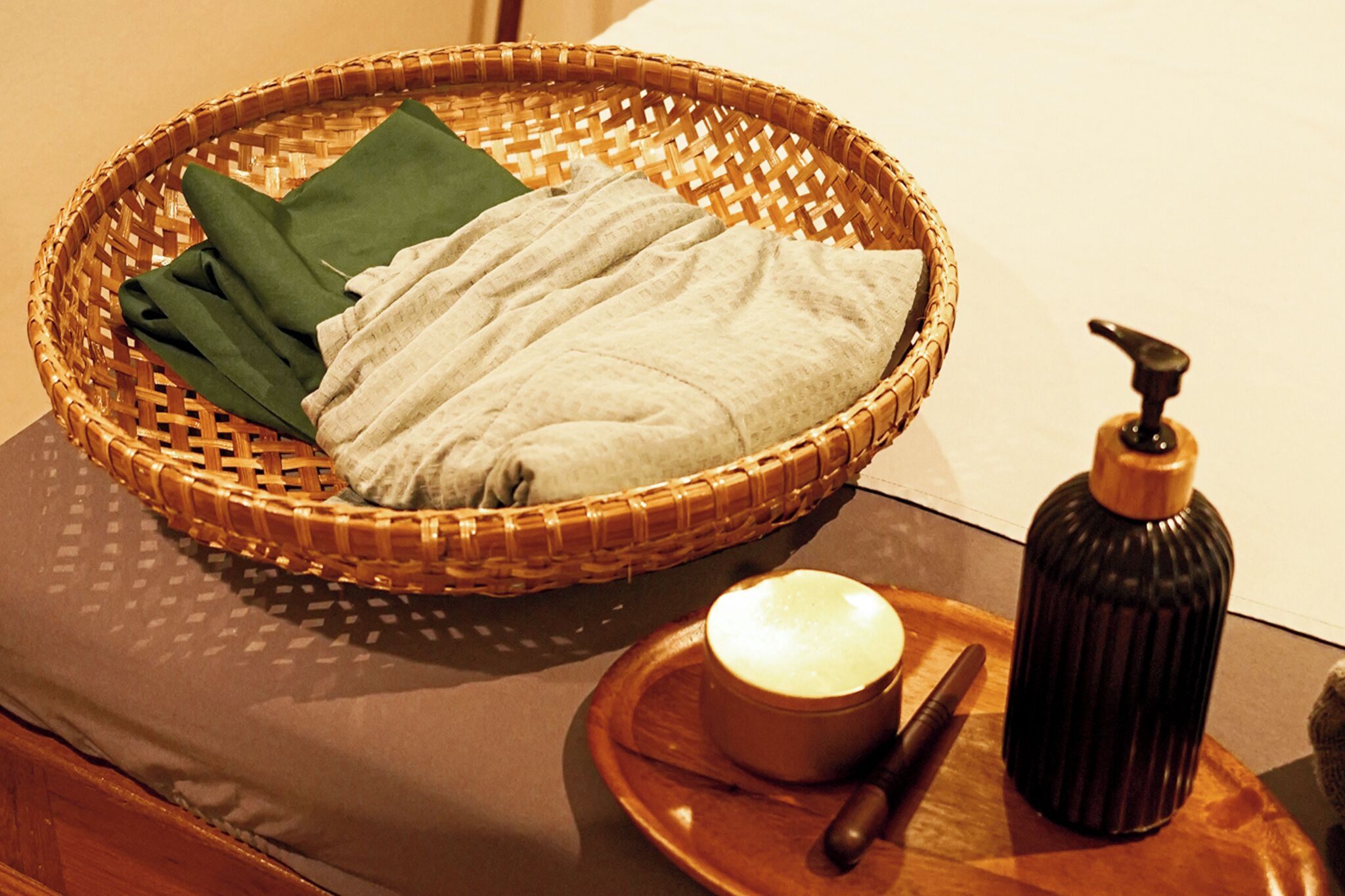 A wicker basket with folded towels and a bottle of soap on a table.