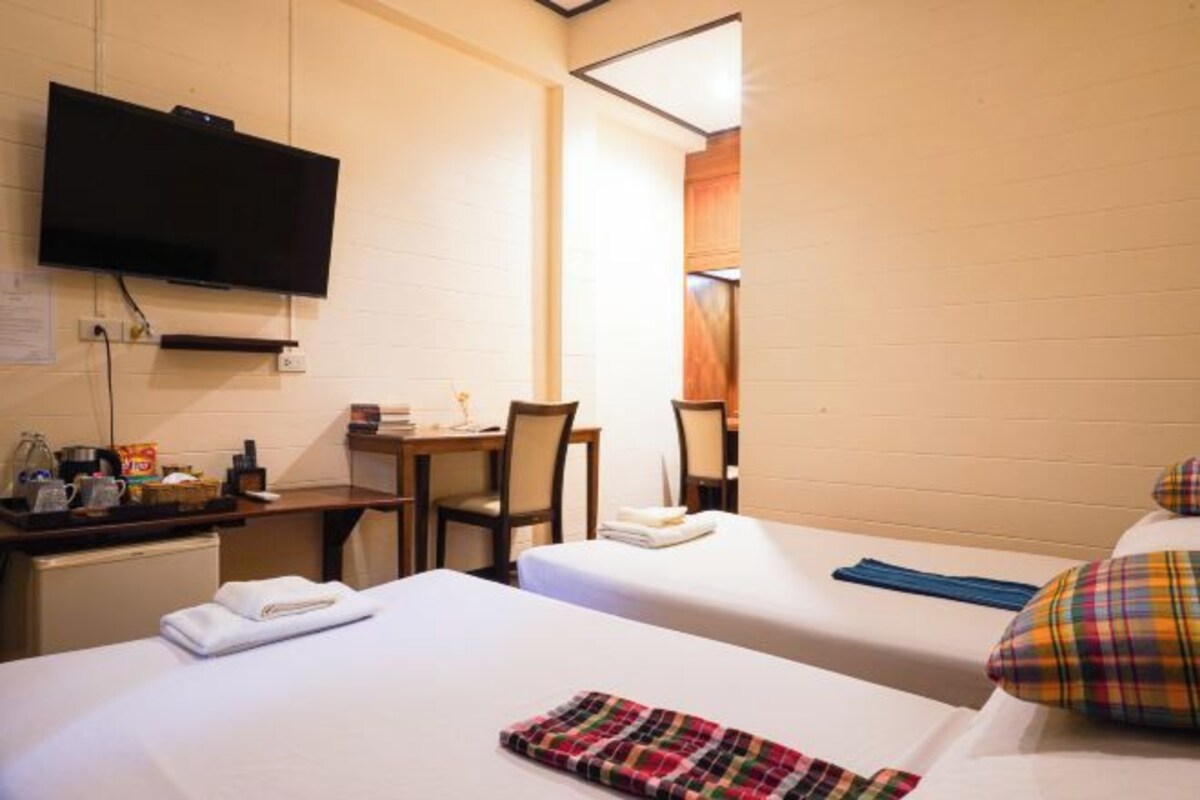 Une chambre d’hôtel avec deux lits, un bureau avec une chaise, un téléviseur fixé au mur et un petit coin cuisine.