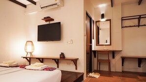 Una habitación de hotel con cama, escritorio, silla, televisor y espejo.