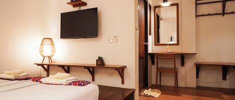 A hotel room with a bed, a desk, a chair, a television, and a mirror.