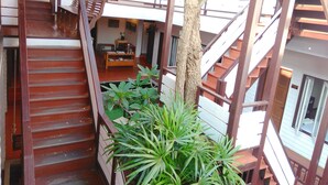 Un interior de varios niveles con escaleras de madera, un comedor y una planta grande.