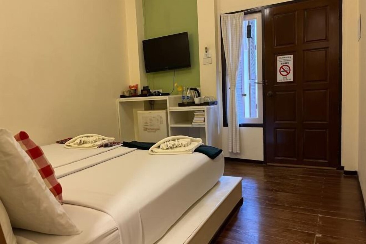 Habitación de hotel con cama, escritorio con computadora, televisor en la pared y puerta con letrero de no fumar.