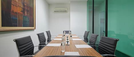 Ein Konferenzraum mit einem langen Tisch, schwarzen Ledersesseln und einem Gemälde an der Wand.