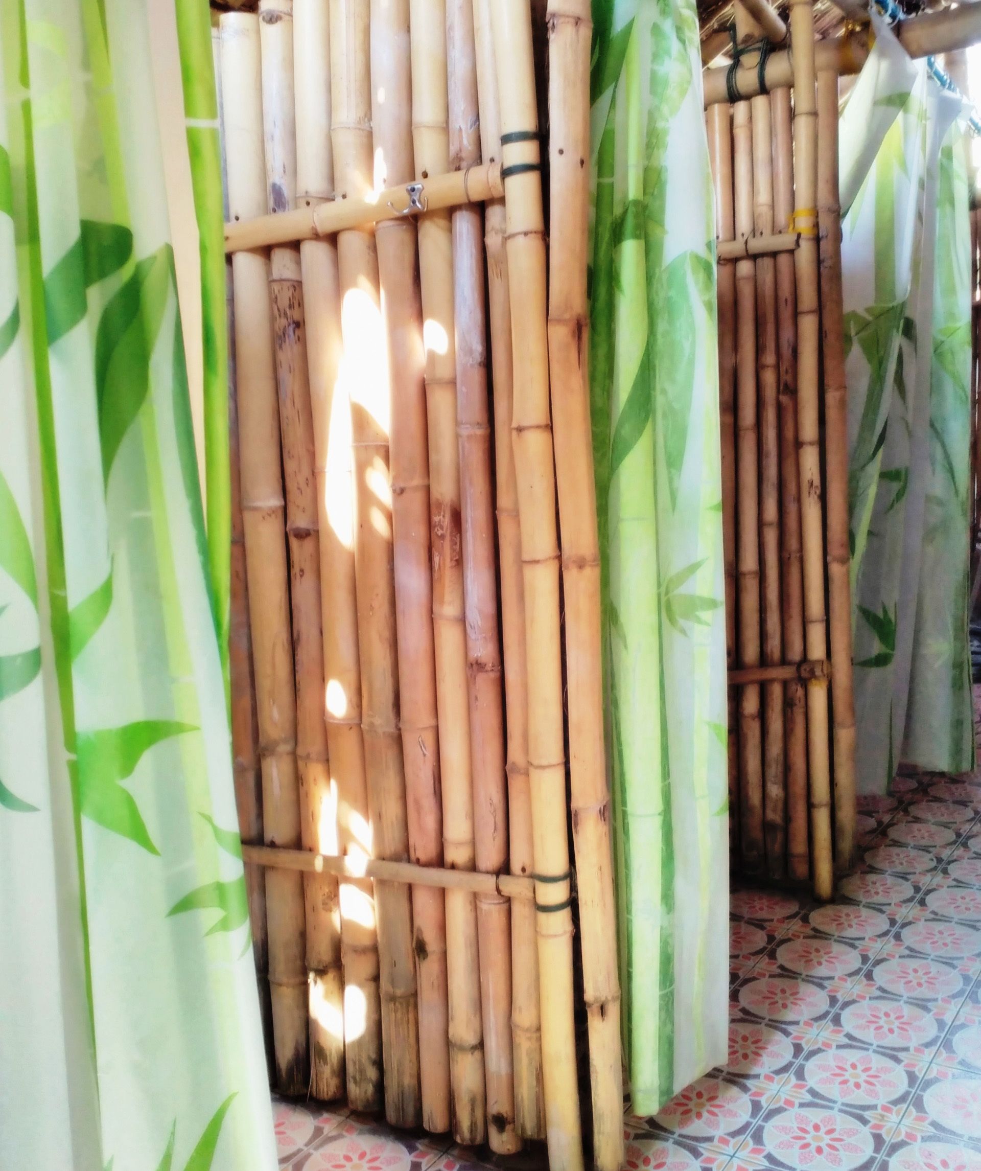 A bamboo partition with a green leaf pattern, a tiled floor, and a ceiling with a decorative element.