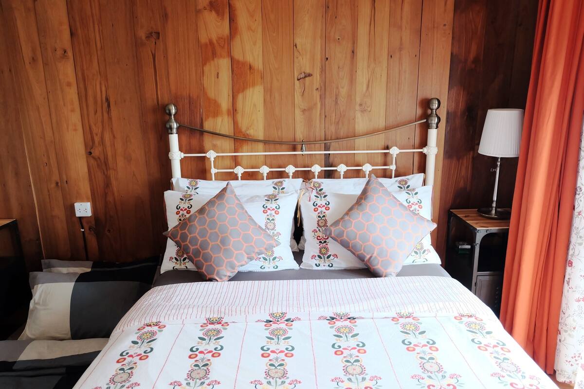 A bed with a white metal frame, floral-patterned bedding, and decorative pillows.