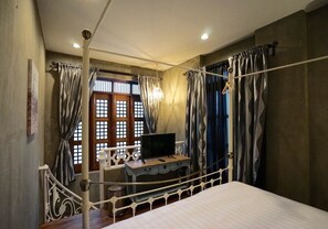 A bedroom with a bed, a TV on a dresser, and a window with curtains. - House of Passion Amphawa (Amphawa)