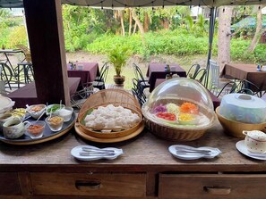 A buffet table with various dishes and utensils, set against a backdrop of lush greenery. - House of Passion Amphawa (Amphawa)