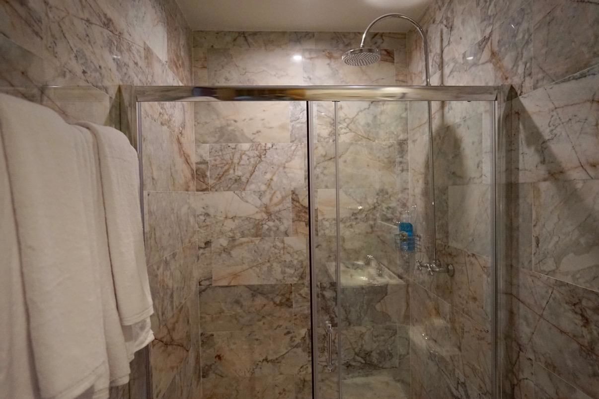 Una cabina doccia in vetro con pareti in marmo e soffione.