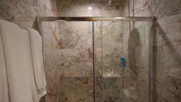Una cabina doccia in vetro con pareti in marmo e soffione.