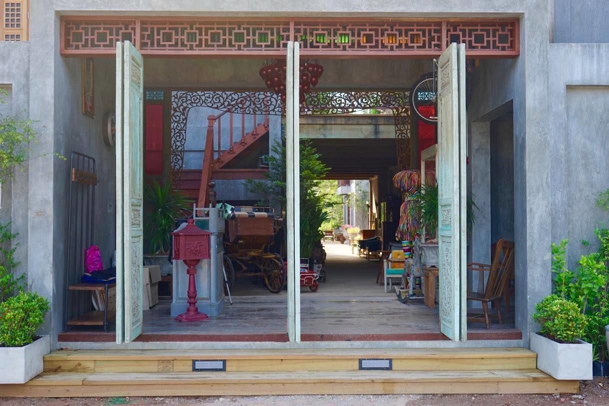 A shop with a wooden staircase leading inside, various items on display, and a bicycle parked outside.