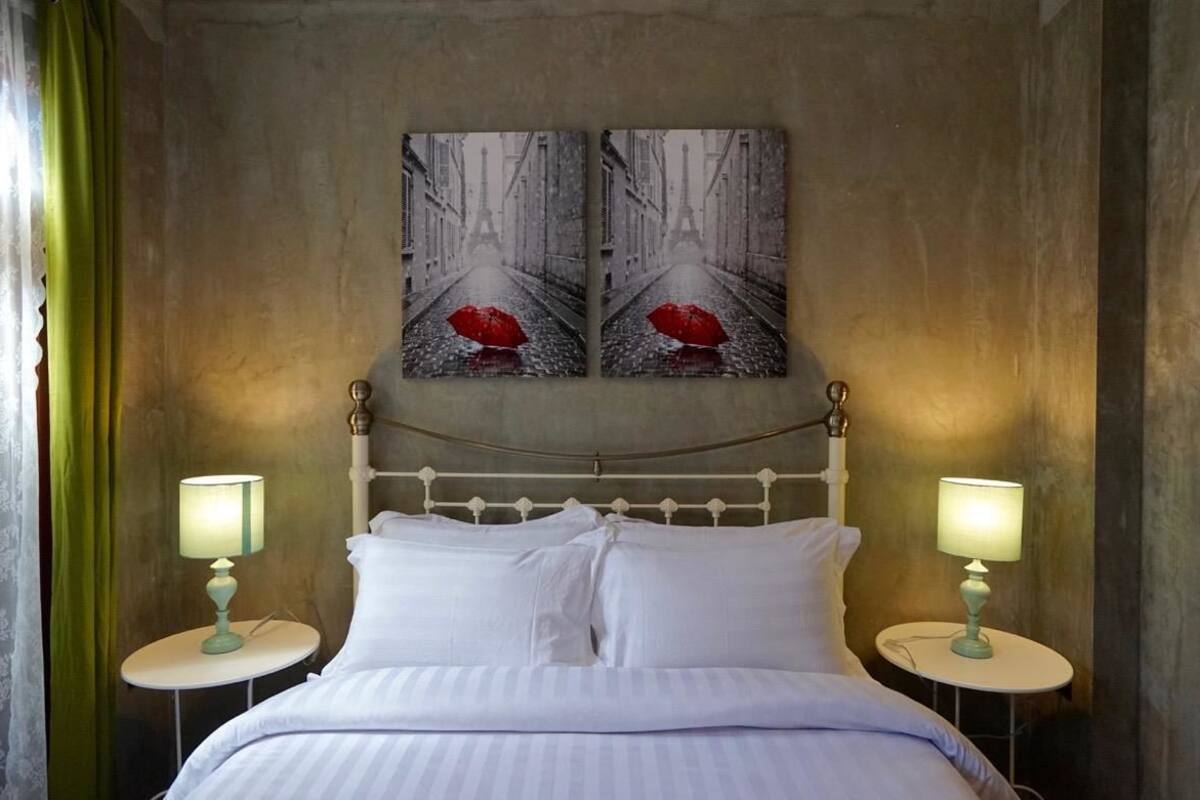 Ein Schlafzimmer mit einem Bett, zwei Nachttischen mit Lampen und zwei an der Wand hängenden Bildern.