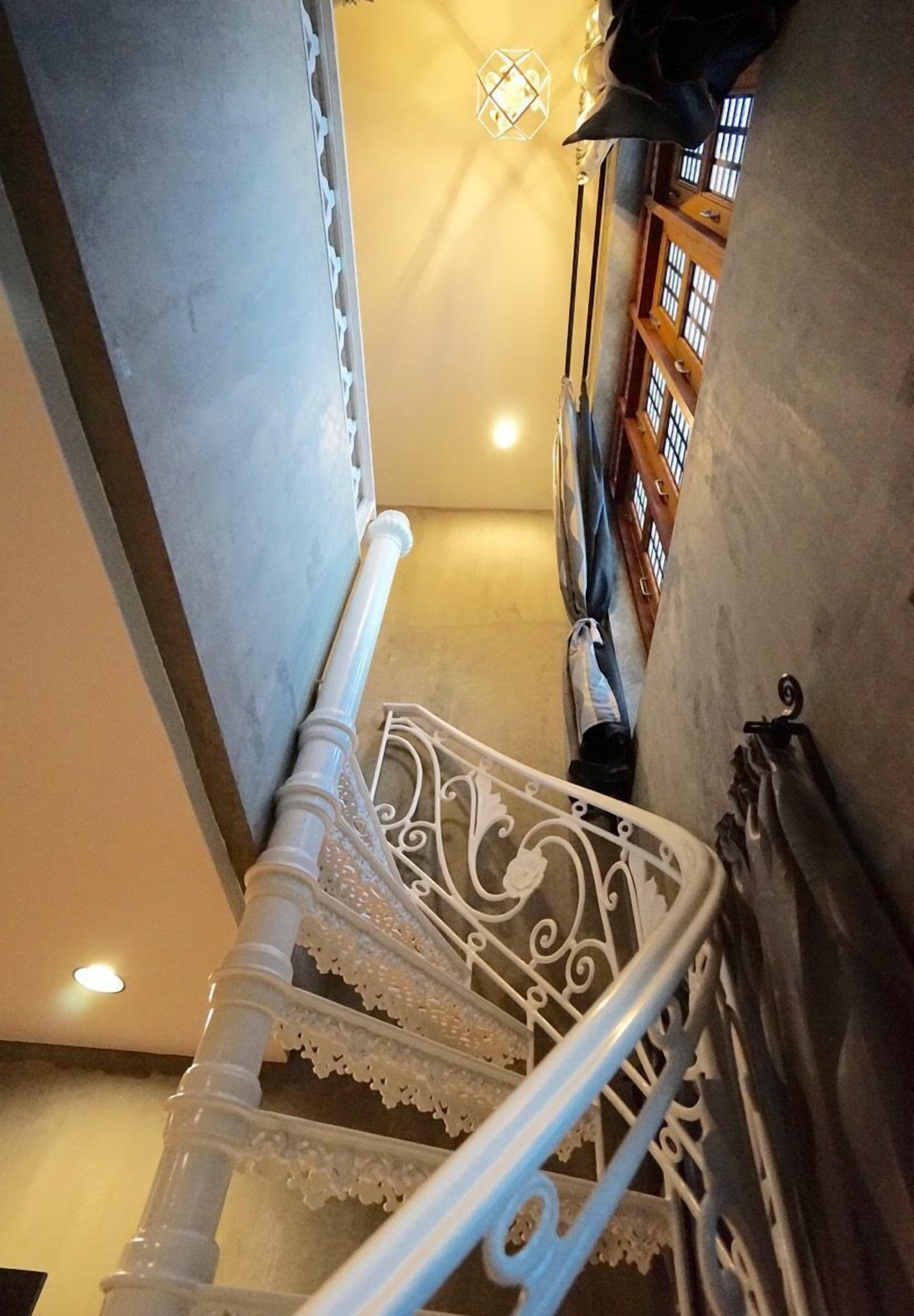 Una escalera con barandillas blancas ornamentadas y piso estampado.