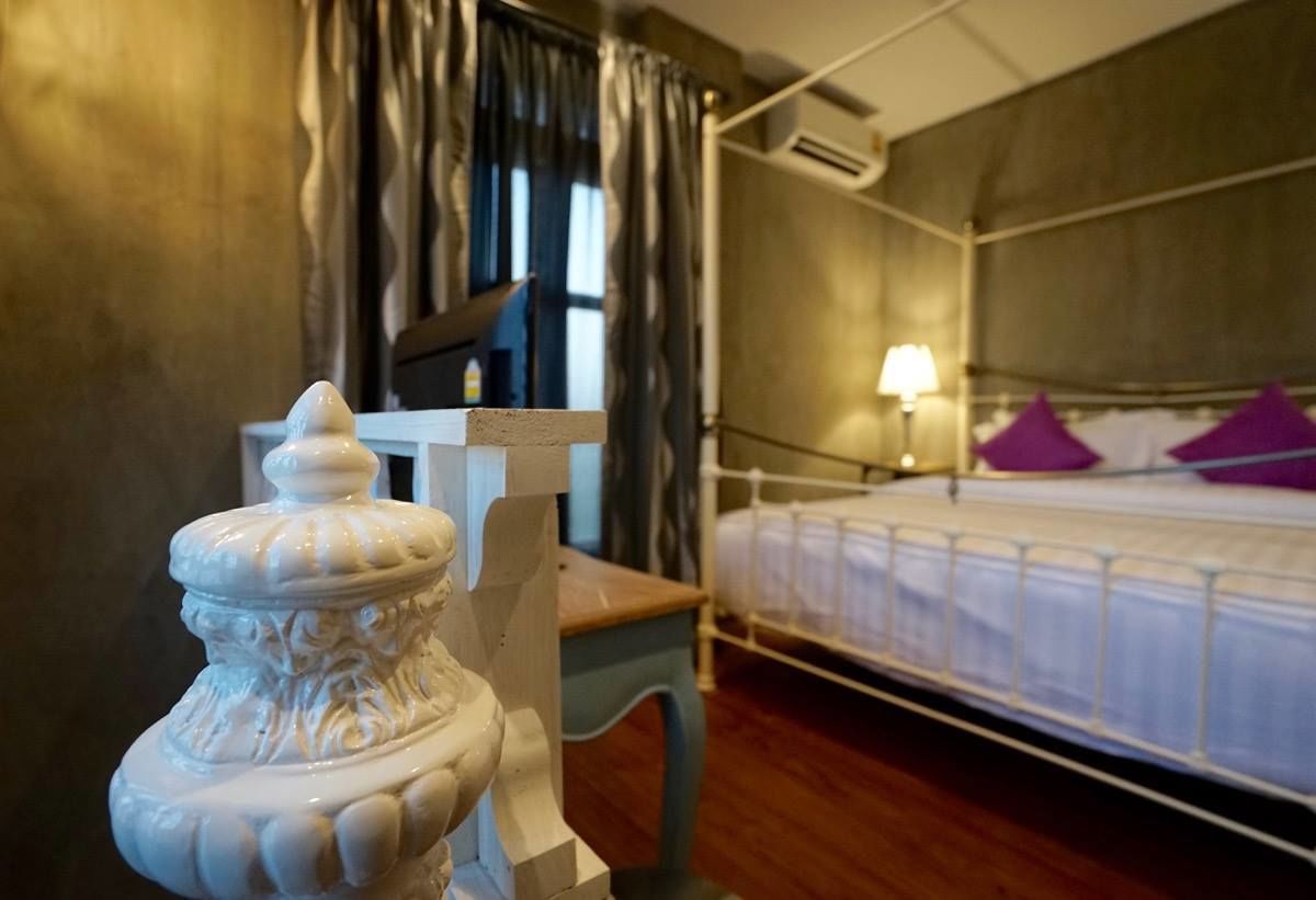 A hotel room with a bed, a nightstand, a lamp, and a decorative item on the nightstand.