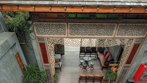 Una terraza de madera con asientos y plantas en macetas, que conduce a un área cubierta con techo de baldosas.