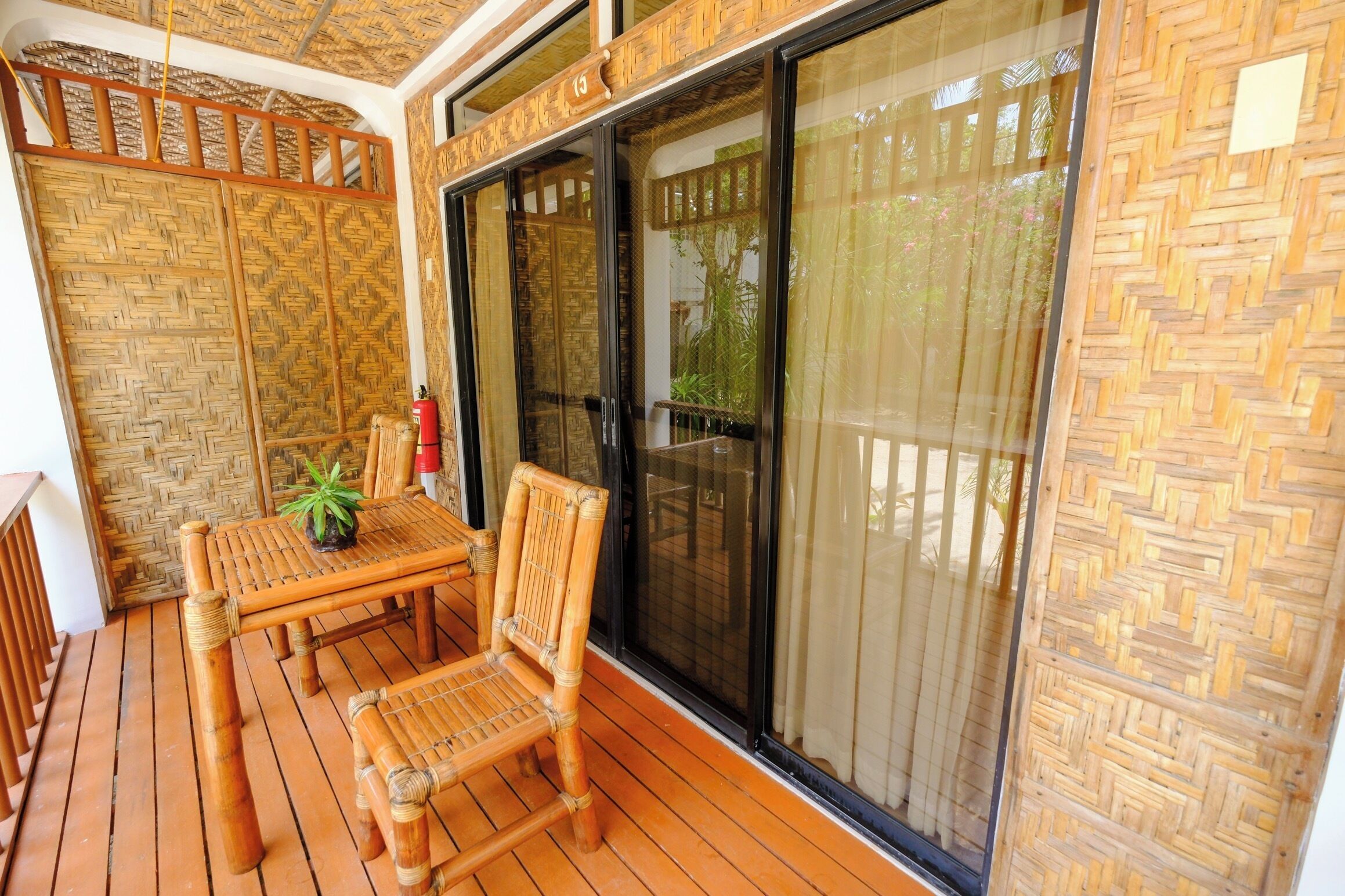 A wooden deck with a table and chairs, a potted plant, and a sliding glass door.