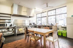 A modern kitchen with stainless steel appliances, a wooden dining table, and a large window offering a view of the city. - Downtown Backpackers Hostel - note - Valid Passport required for check in (East Perth)