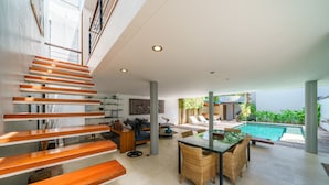 A modern interior with a staircase, dining area, and a pool. - Villa Rio (Seminyak)