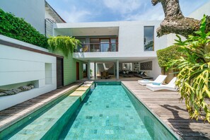 A modern house with a swimming pool, a wooden deck, and a second-story balcony. - Villa Rio (Seminyak)