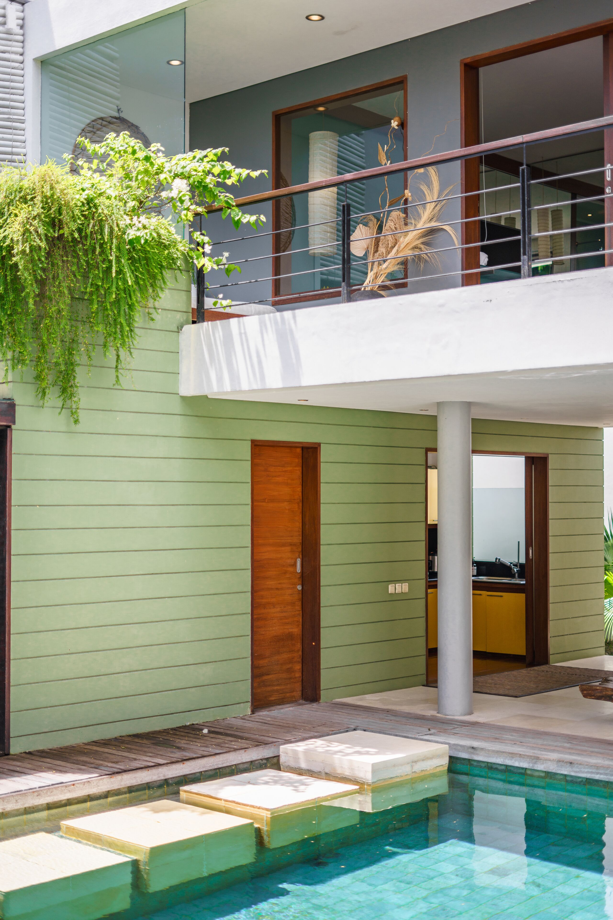 A modern building with a pool, a balcony with a railing, and a door.
