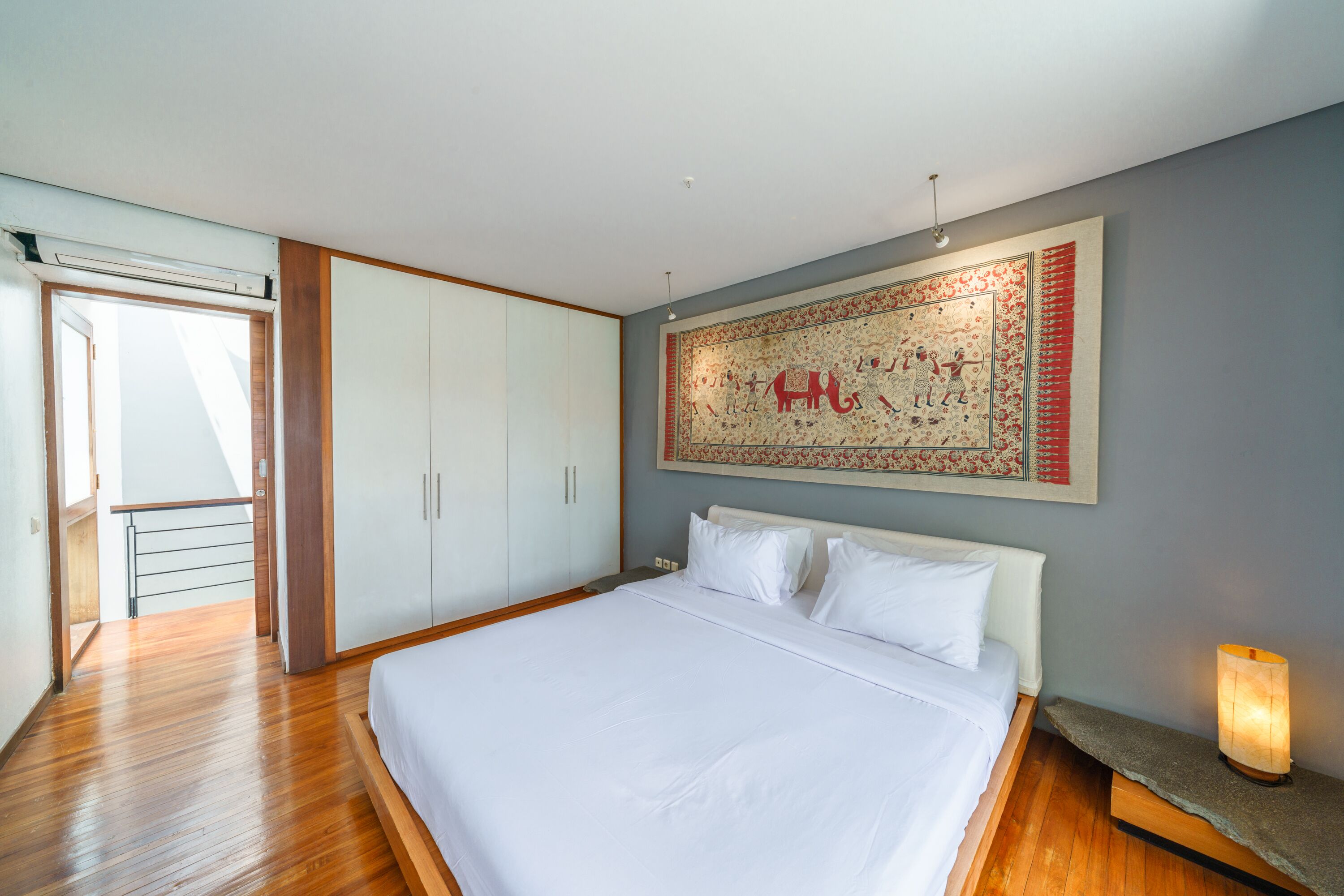Een slaapkamer met een groot bed, een kledingkast en een wandtapijt.