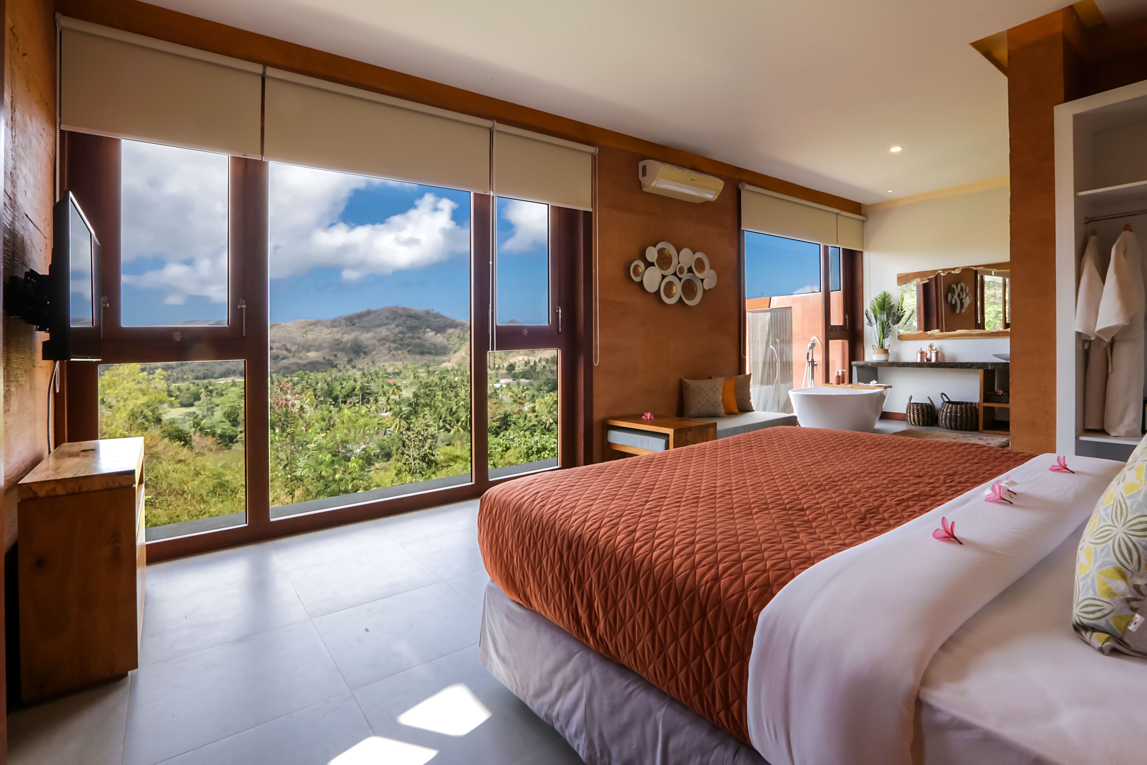 Un dormitorio amplio con una cama grande, un baño con bañera y vistas a un paisaje montañoso.