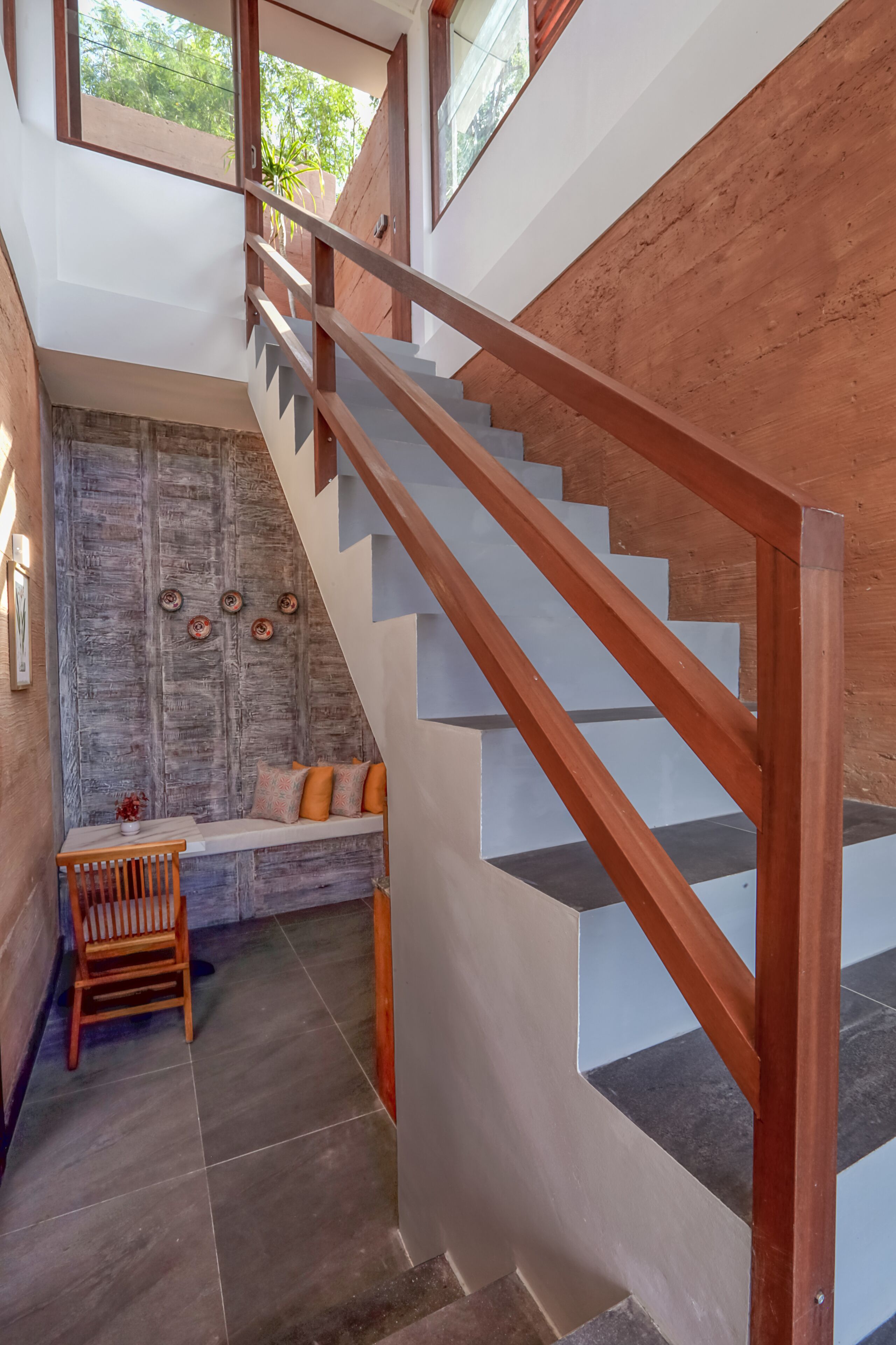 Eine Treppe mit Holzgeländern führt zu einer Empore mit einer Bank und einem Stuhl.