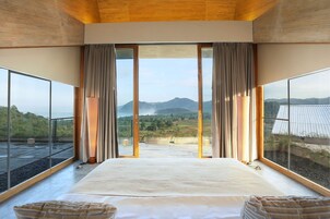 Un dormitorio con una cama grande, vistas a montañas y un balcón.