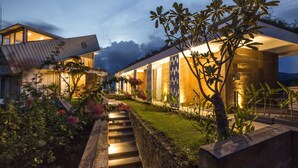 Une maison moderne dotée d’une architecture originale, caractérisée par un toit en pente et une façade bien éclairée.