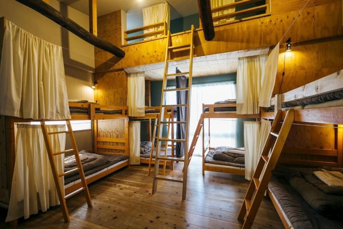 A room with bunk beds, wooden ladders, and curtains.