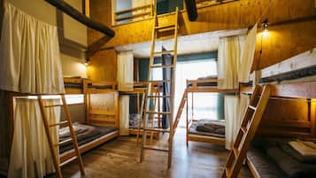 A room with bunk beds, wooden ladders, and curtains.