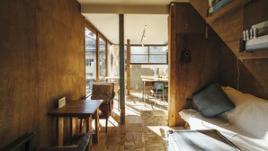 Une pièce confortable avec un plancher en bois, un lit avec un oreiller, un bureau et une chaise.