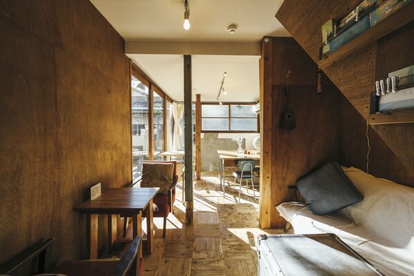 A cozy room with a wooden floor, a bed with a pillow, a desk, and a chair. - Torii-Kuguru Hostel (Okayama)