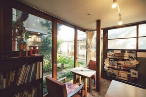 A room with a large window, a bookshelf, a table with a chair, and a bulletin board with papers. - Torii-Kuguru Hostel (Okayama)
