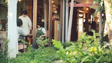 A cozy outdoor seating area with a wooden table and chairs, surrounded by greenery.