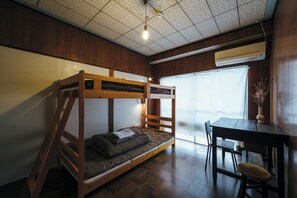 Una cama individual con escritorio y silla, una ventana con vistas y un equipo de aire acondicionado.