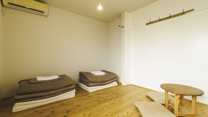Une pièce avec un plancher en bois, une petite table en bois et une pile de couvertures pliées.