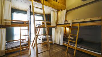Un dormitorio con literas, suelo de madera y una escalera.