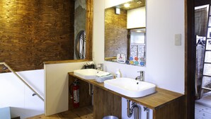 Une salle de bain avec un lambris en bois, deux lavabos, un miroir et un extincteur.