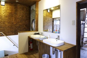 A bathroom with wooden paneling, two sinks, a mirror, and a fire extinguisher. - Torii-Kuguru Hostel (Okayama)