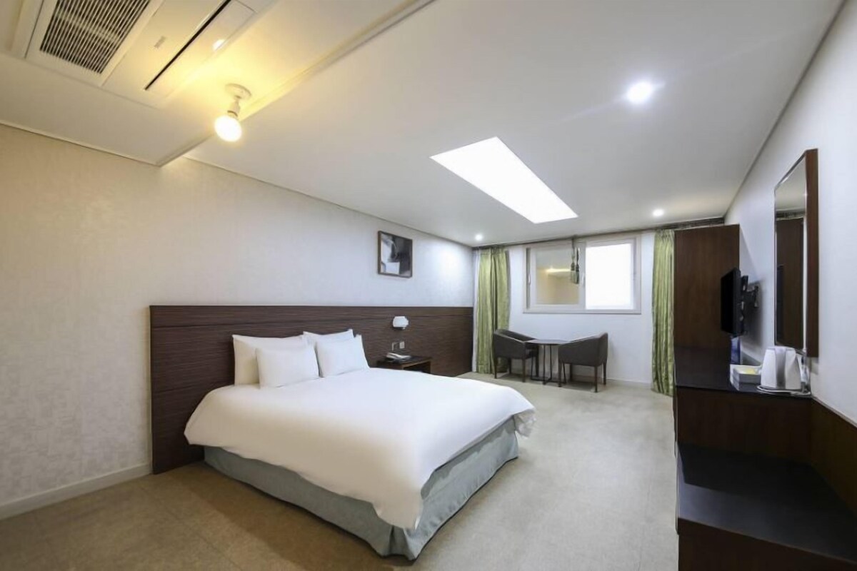 Une chambre d’hôtel avec un lit, un bureau, une chaise et un miroir.