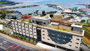 Ein Hotel mit mehreren Stockwerken, einem Parkplatz und Blick auf das Meer und die Docks.