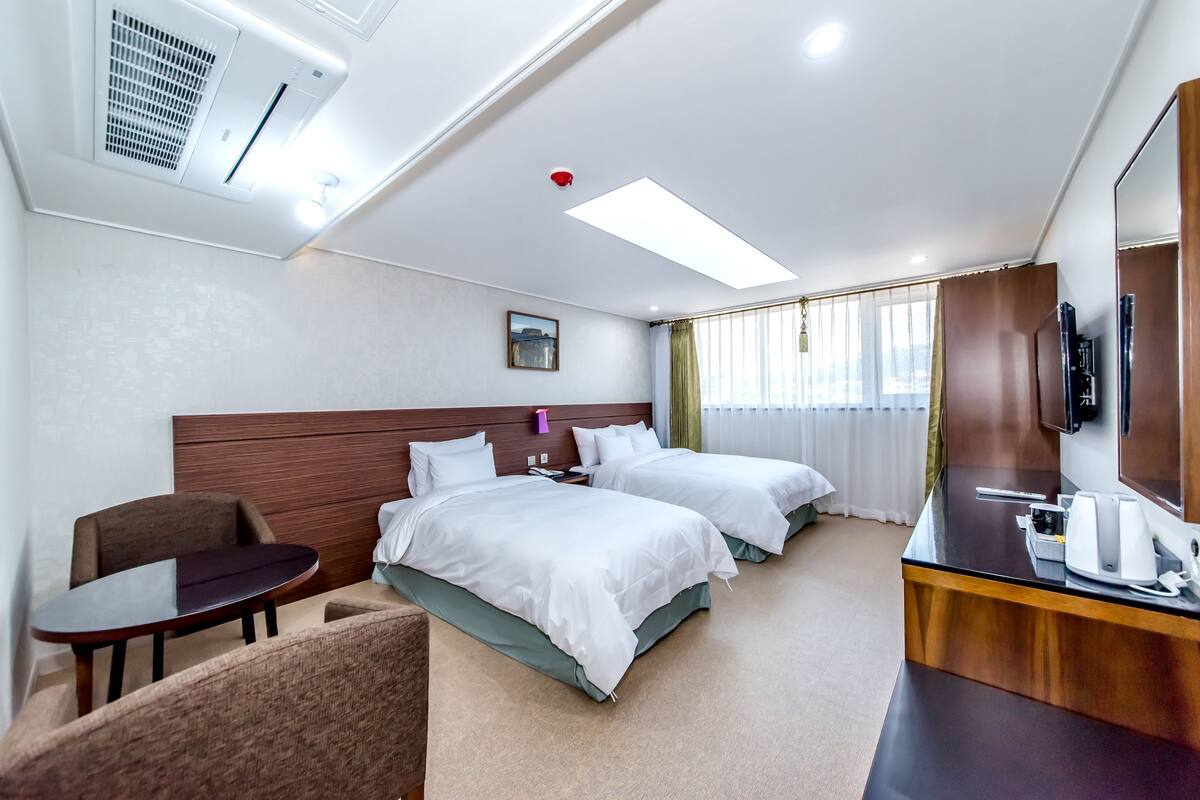 Een hotelkamer met twee bedden, een bureau, een stoel en een televisie.