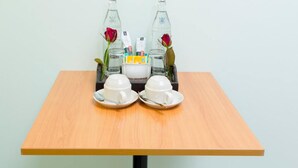 A table with two white cups and saucers, a small tray with a bottle and a rose, and a container with tissues and a small box. - The Garden Place (Nonthaburi)