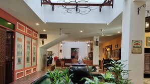 Un espacio interior amplio con una fuente central, suelo de madera y diversas plantas.