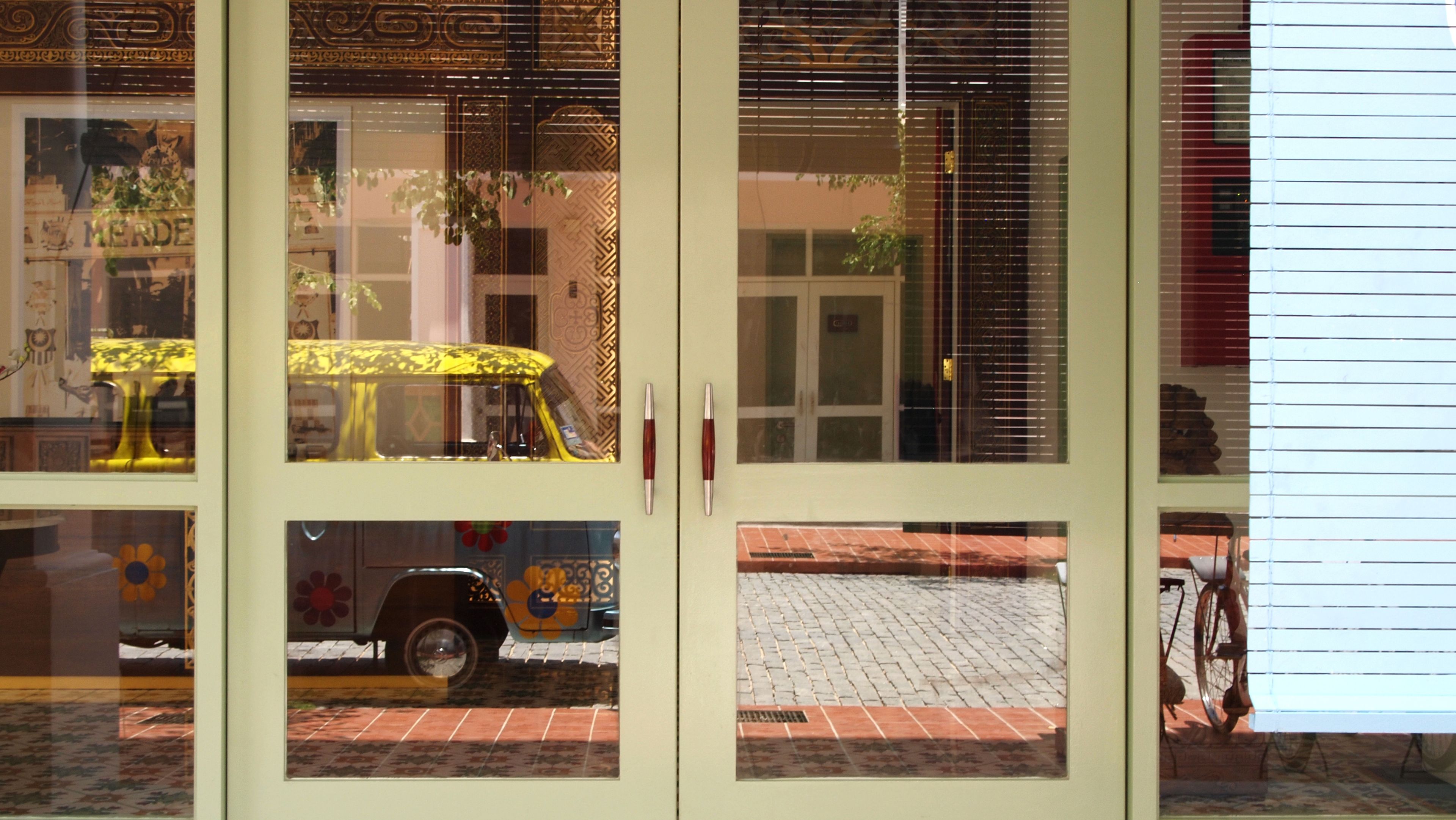 Un bâtiment doté d’une grande porte vitrée qui reflète une voiture jaune et un vélo.