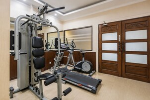 Une salle de sport équipée d’une machine de musculation, d’un tapis de course et d’un miroir.