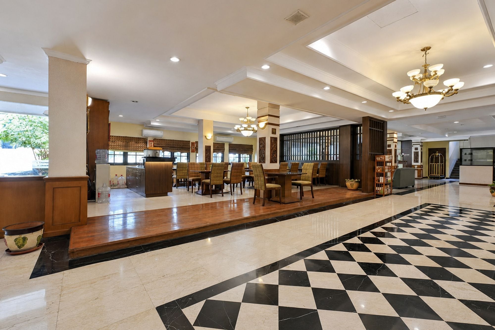 A hotel lobby with a checkered floor, a reception desk, and seating areas.